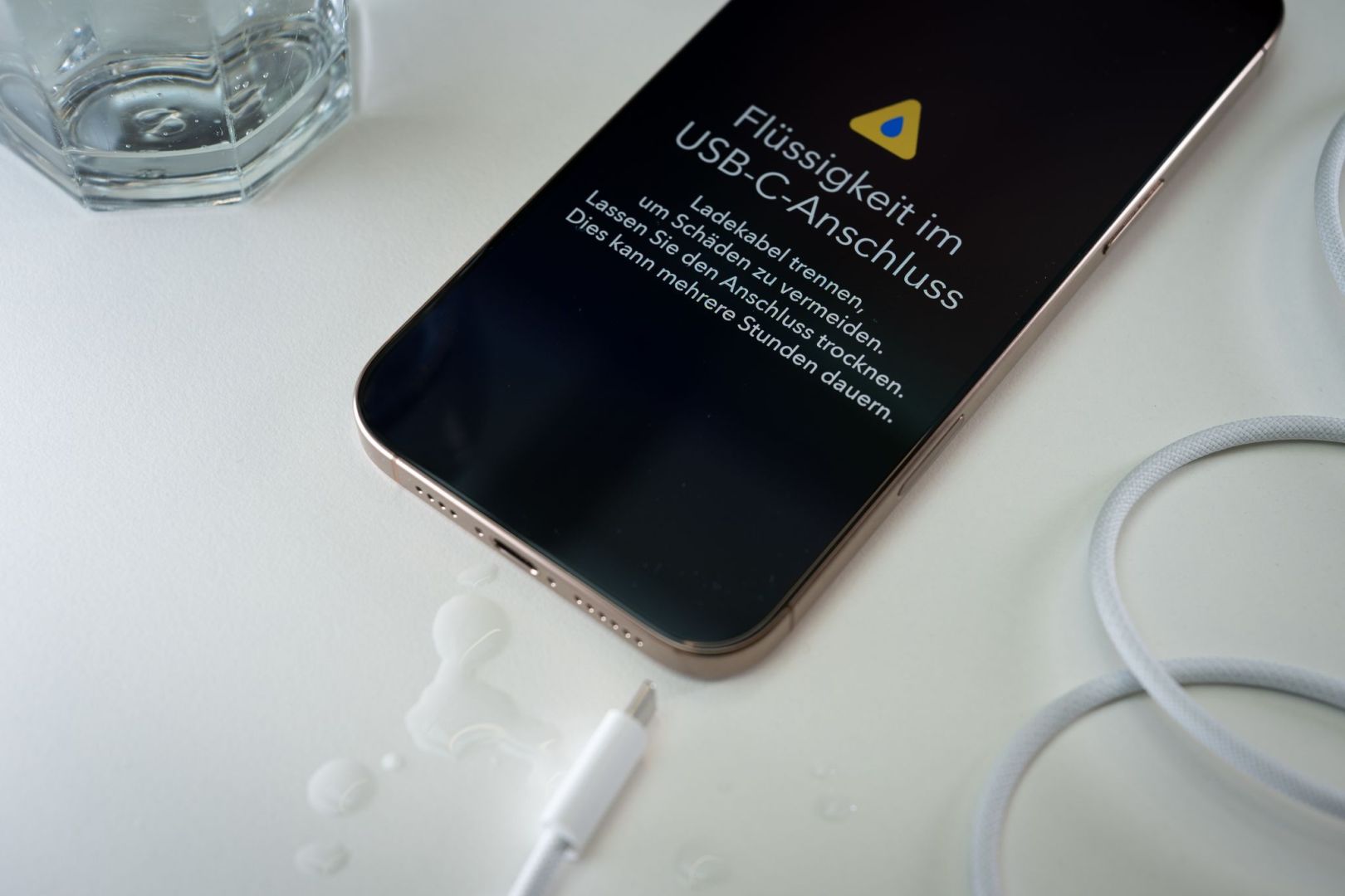 Ein iPhone mit einer Flüssigkeitswarnung und Wassertropfen
