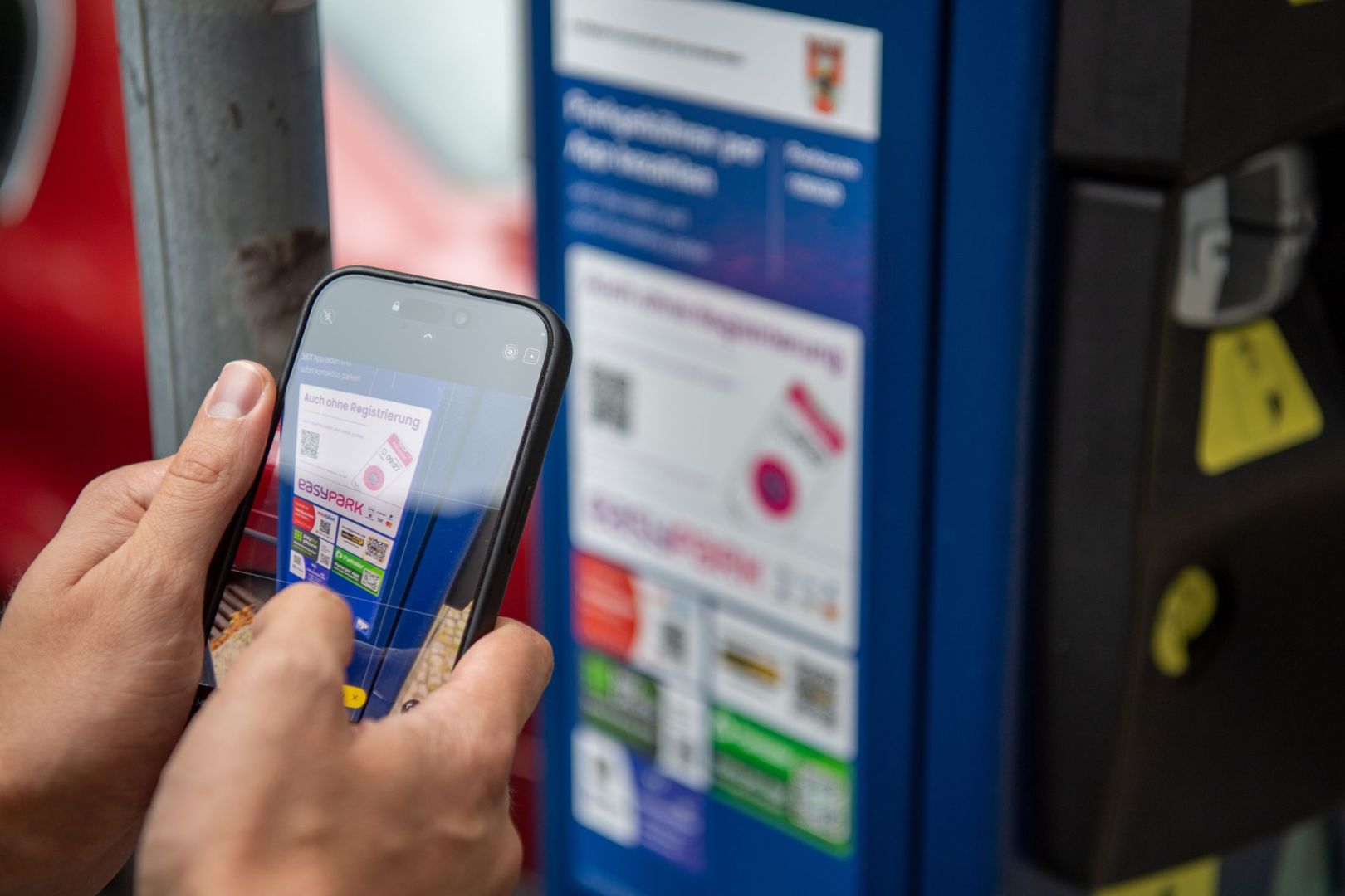 Ein Mann scannt den QR-Code einer Park-App mit einem Smartphone