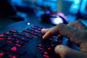 Ein Mann sitzt am Rechner und tippt auf einer Tastatur