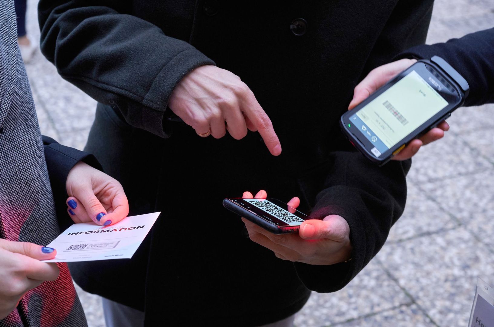 Ein Mann zeigt auf einen QR-Code den eine Frau Scannt