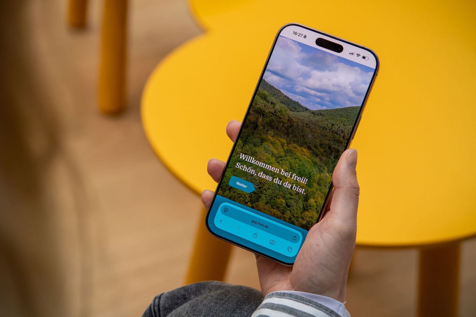 Eine Frau haelt ein Handy mit der Web-App «freii» in der Hand