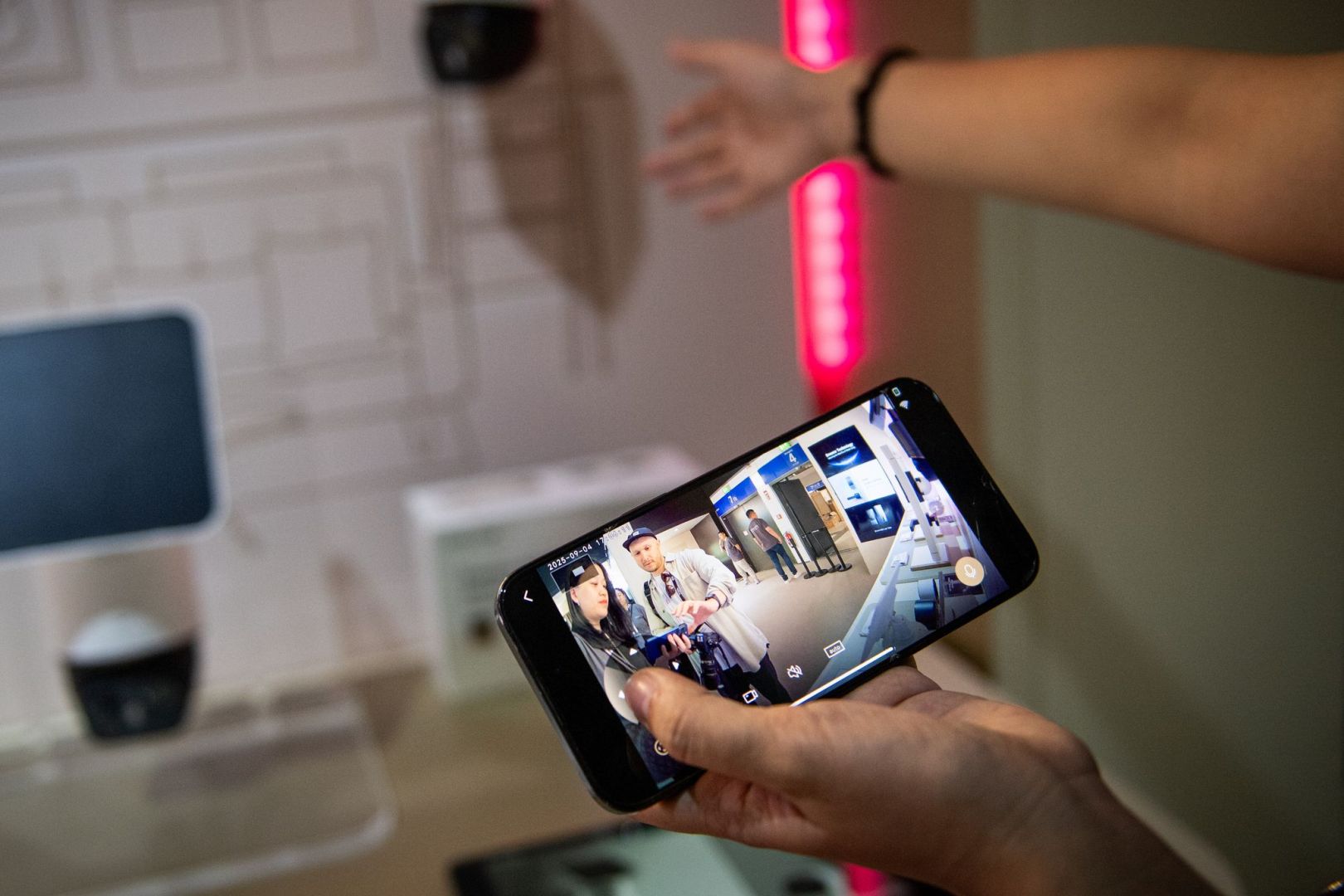 Eine Frau steuert mit einem Smartphone eine Ueberwachungskamera