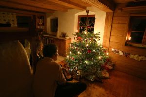 Familie sitzt vor einem beleuchteten Weihnachtsbaum