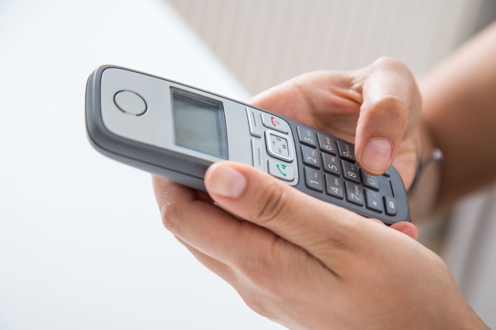 Frau hält ein Festnetztelefon in den Händen