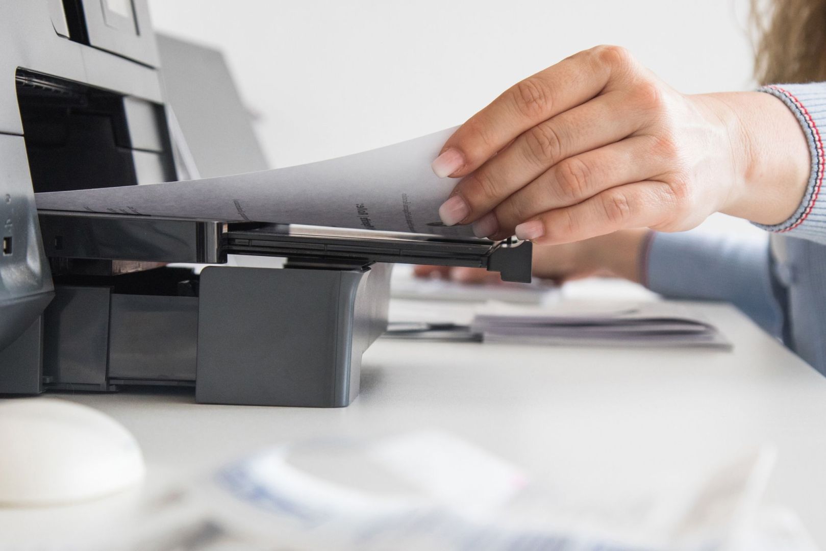 Frau nimmt ein Blatt Papier aus einem Drucker