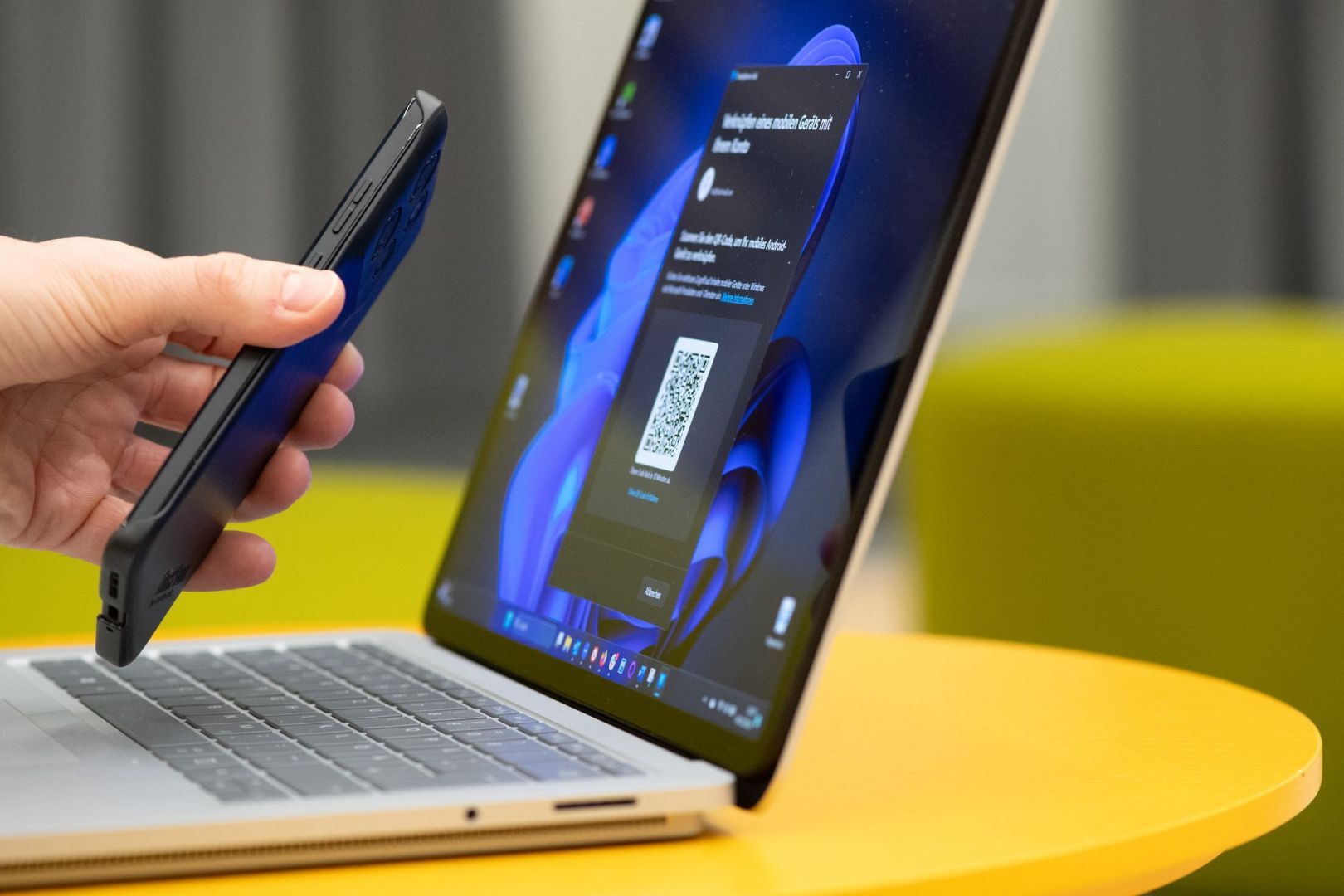 Mann scannt mit Smartphone einen QR-Code von einem Laptop