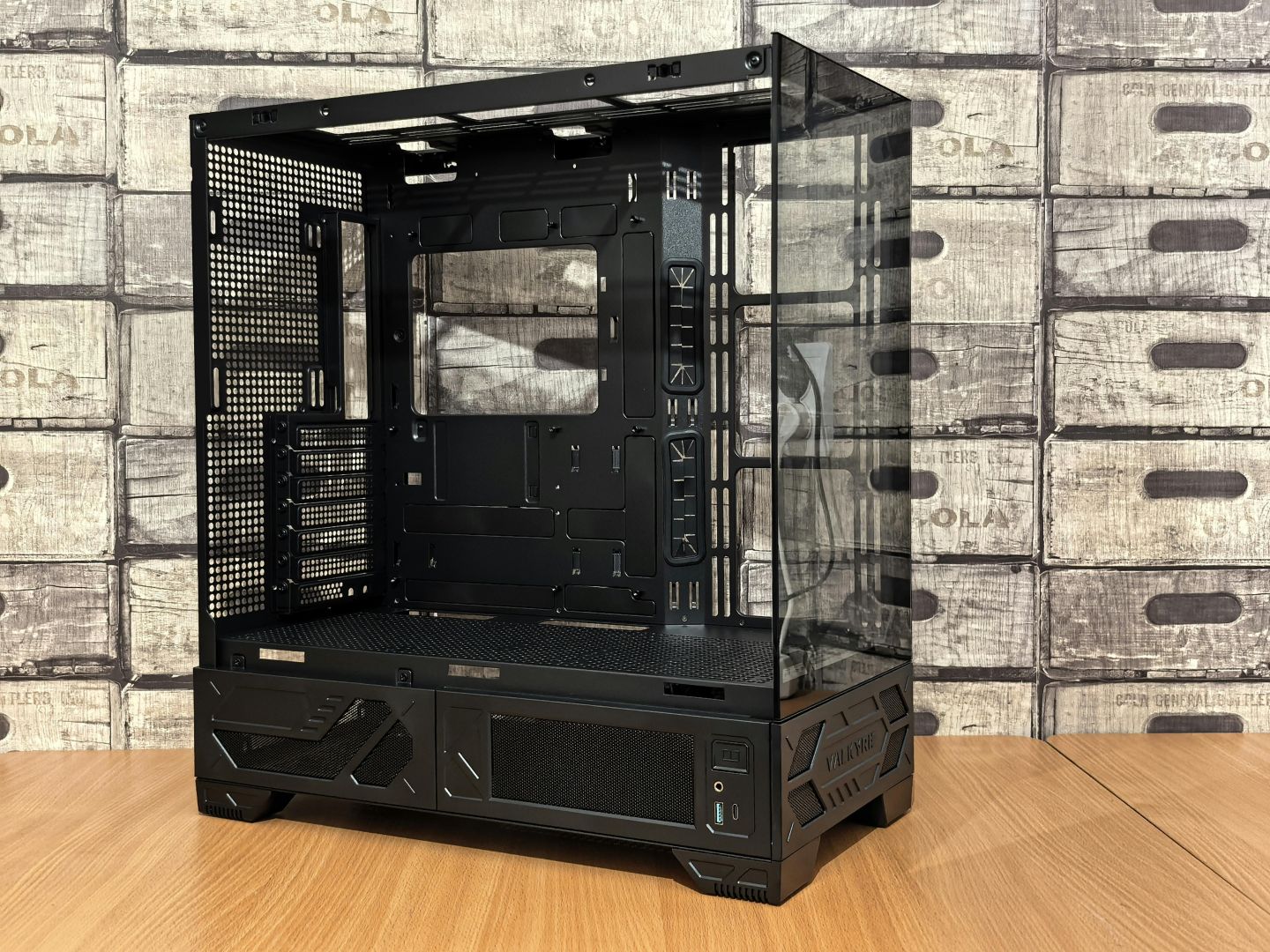 Modernes schwarzes PC-Gaming-Tower-Gehäuse mit gehärteten Glasplatten auf Holztisch, ideal für individuelle Builds.