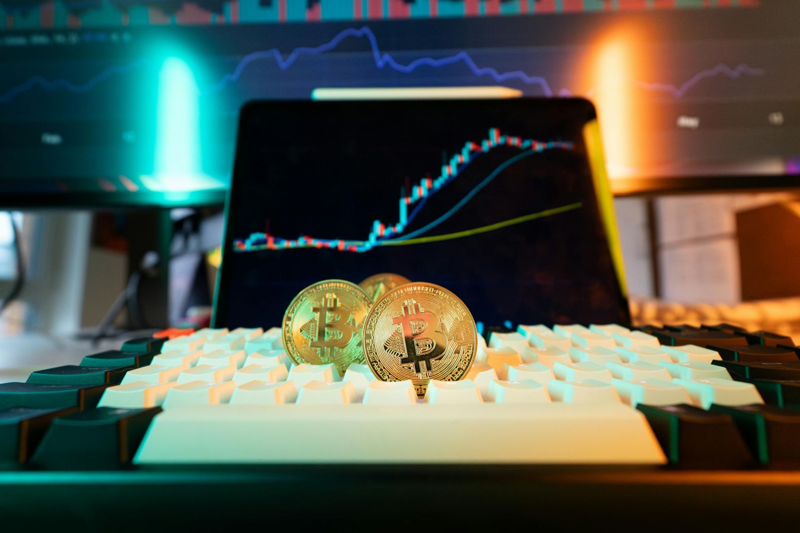 Nahaufnahme von Bitcoin-Münzen auf einer Tastatur mit einem Handelsdiagramm im Hintergrund