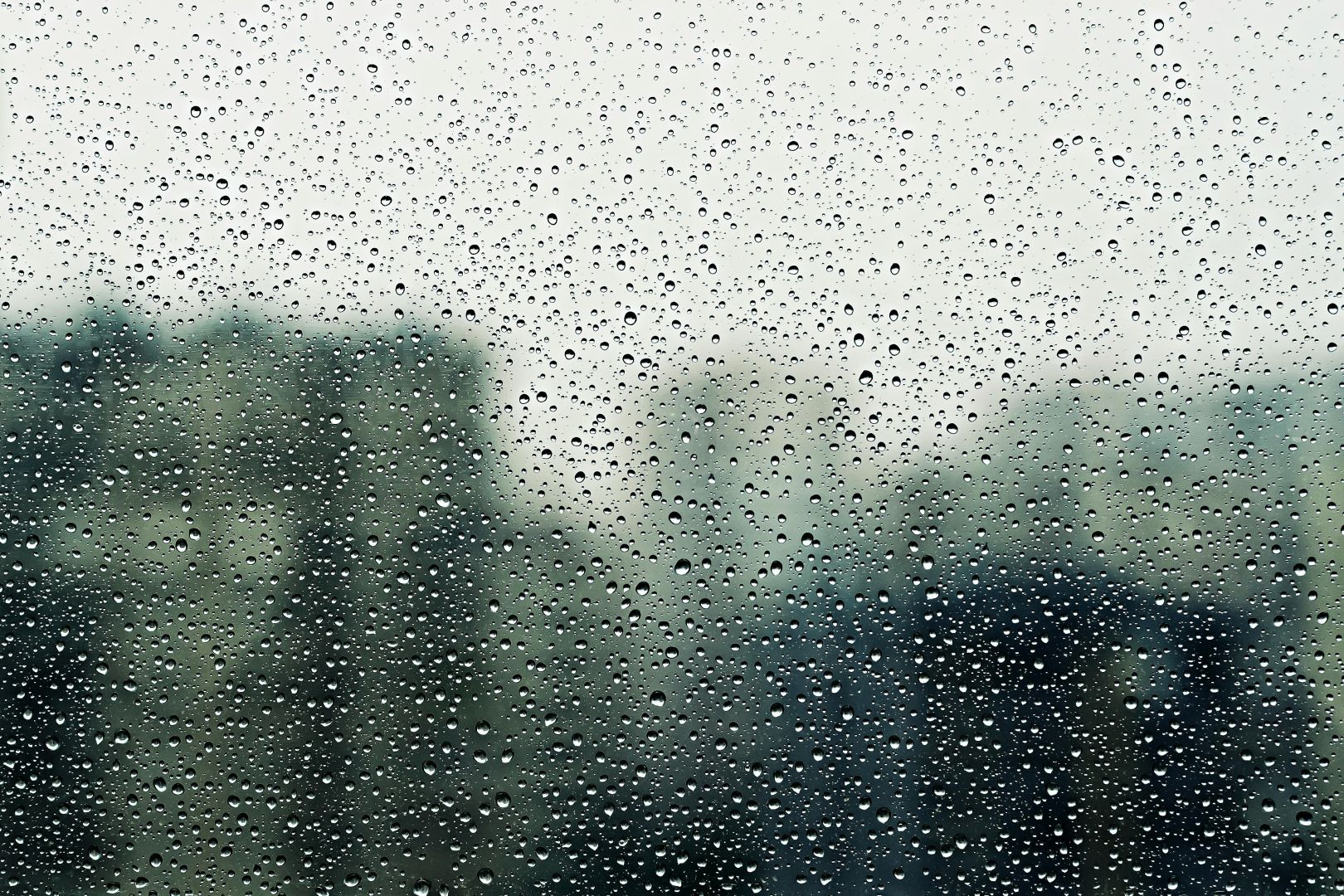 nahaufnahme von regentropfen auf einem fenster mit unscharfem hintergrund, die eine stimmungsvolle, gemütliche atmosphäre vermitteln.