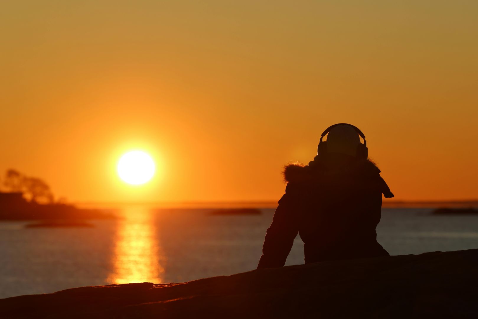 Person genießt einen friedlichen Sonnenaufgang im Cove Island Park in Stamford. Perfekt für Entspannungs- und Meditationsthemen.