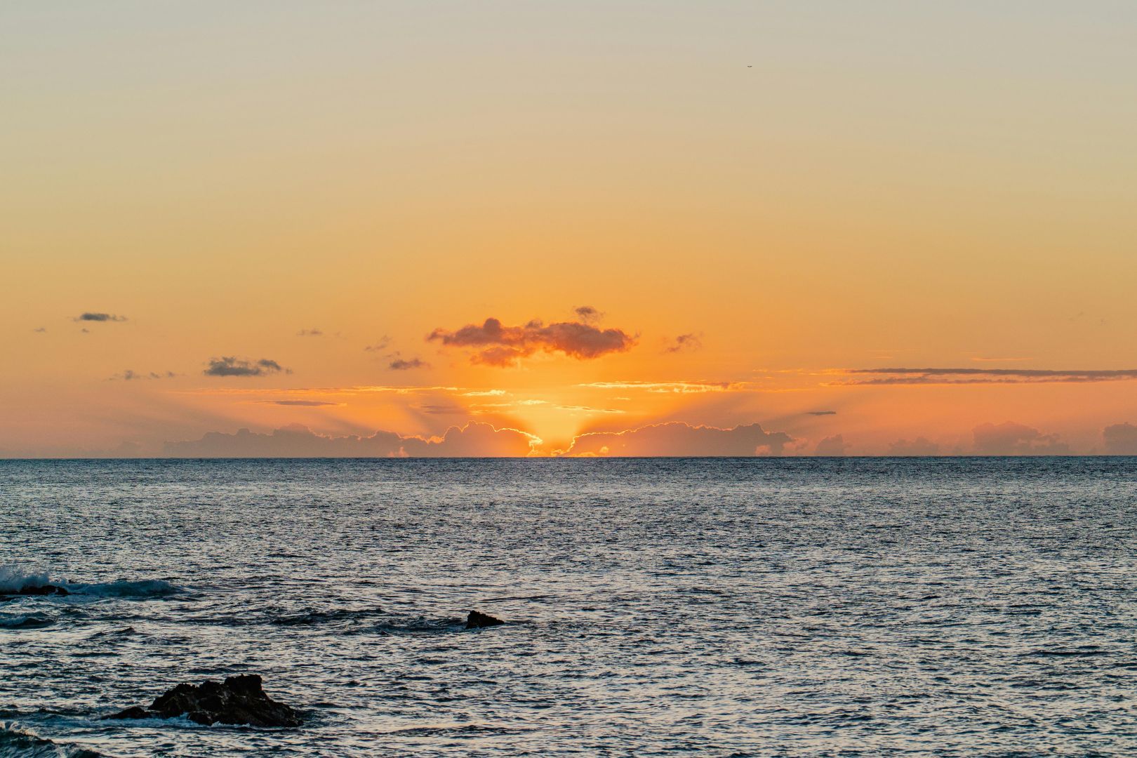 Atemberaubender Hawaii-Sonnenuntergang mit leuchtenden Orangetönen über dem ruhigen Pazifik.
