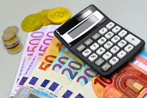 Bild von Euro-Banknoten, Münzen und einem Rechner für die Finanzplanung. Perfekt für Finanzthemen.