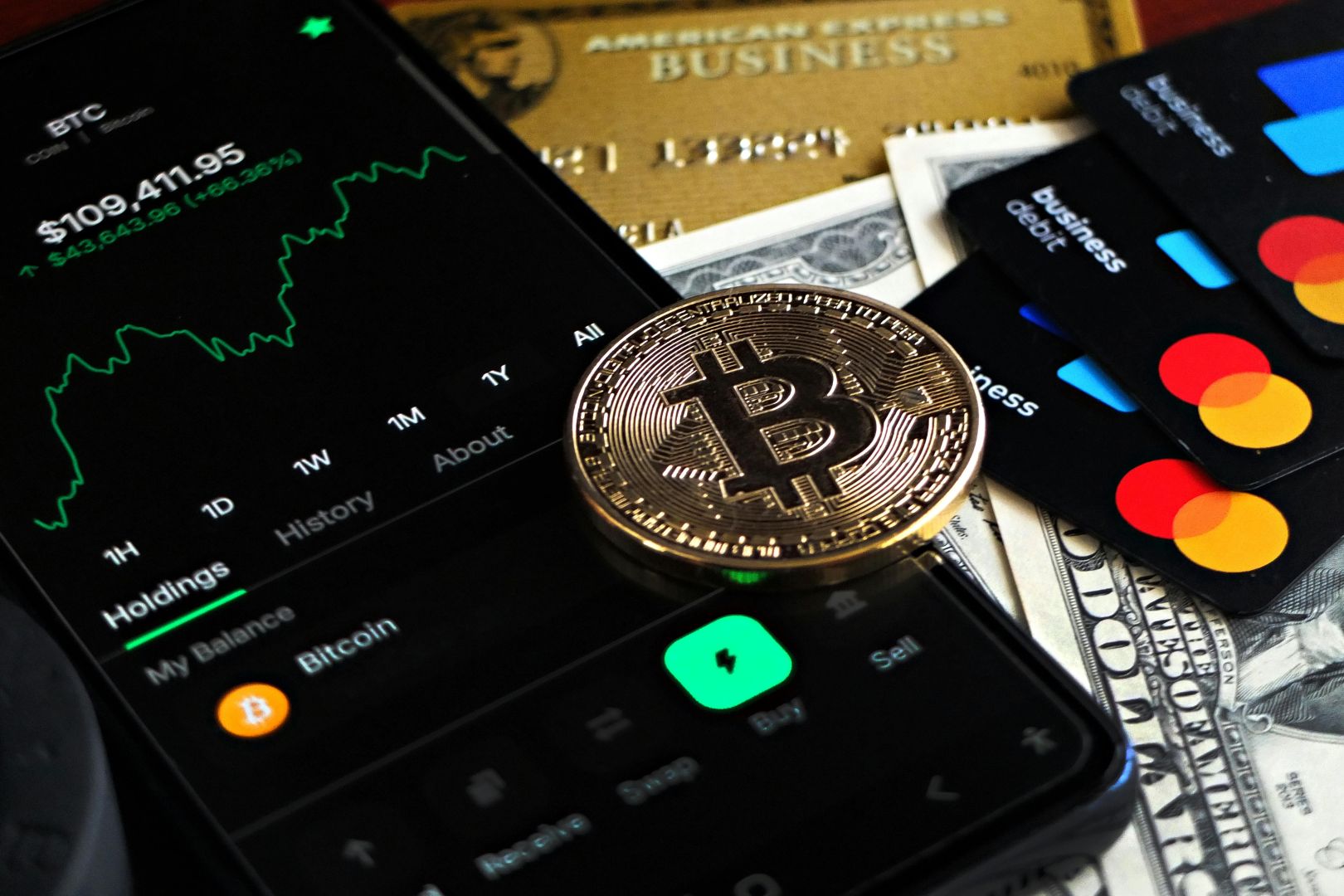 Bitcoin-Münze mit Finanzdaten, Kreditkarten und Währung auf einem Schreibtisch.