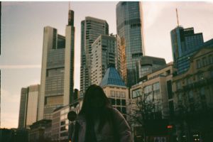 Die Silhouette einer Person, die bei Sonnenuntergang vor der Skyline einer modernen Stadt steht und eine dramatische urbane Szene erzeugt.