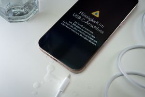 Ein iPhone mit einer Flüssigkeitswarnung und Wassertropfen