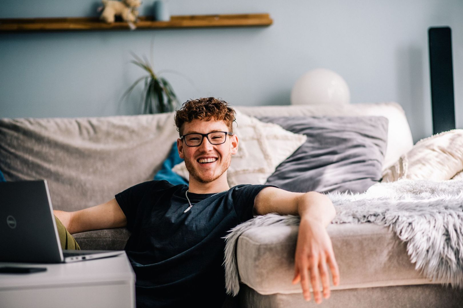 Ein Jugendlicher sitzt im Wohnzimmer vor einem Laptop