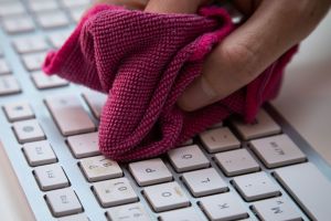 Ein Mann reinigt eine Tastatur mit einem Mikrofasertuch