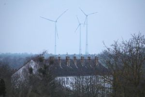 Ein Mehrfamilienhaus mit Windrädern im Hintergrund (Archiv)