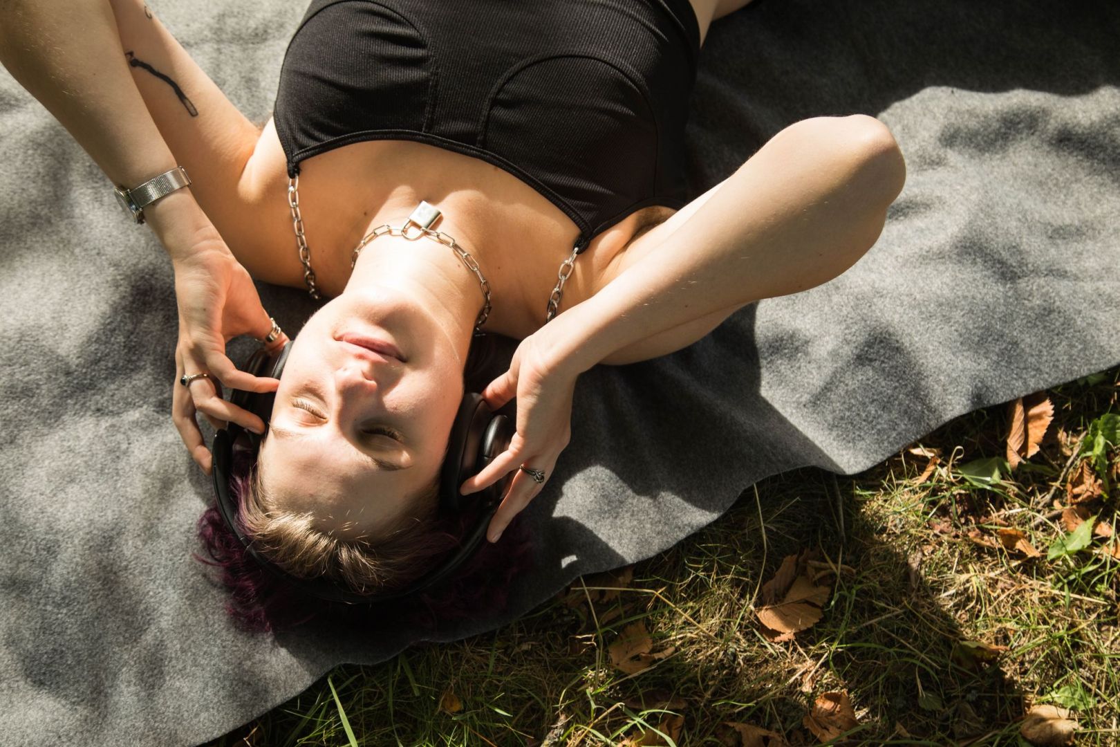 Eine diverse Person mit Kopfhörern im Park