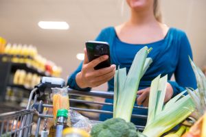 Eine Frau mit Smartphone im Supermarkt