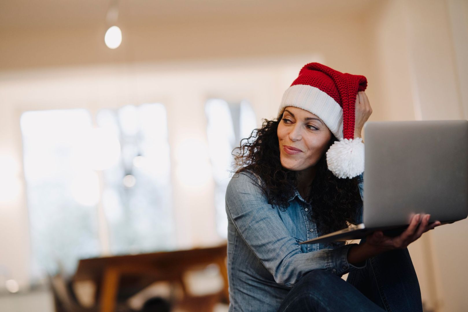 Eine Frau mit Weihnachtsmütze am Laptop