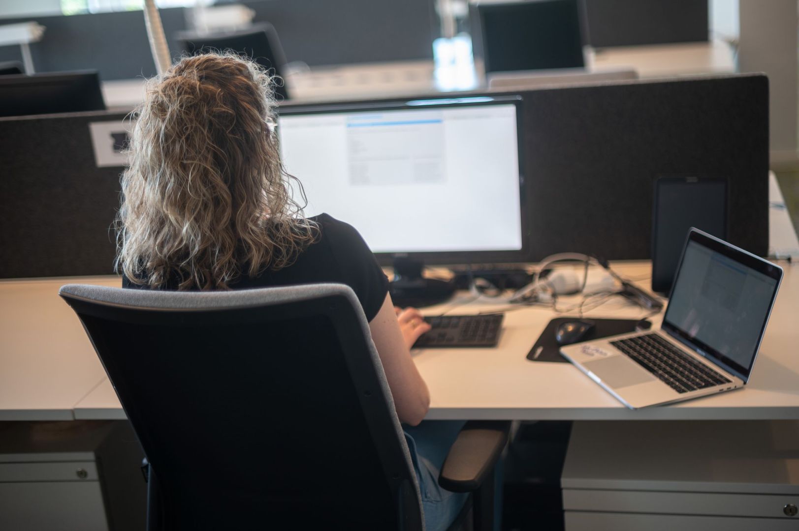 Eine Frau sitzt am Schreibtisch vor einem Bildschirm