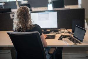 Eine Frau sitzt am Schreibtisch vor einem Bildschirm