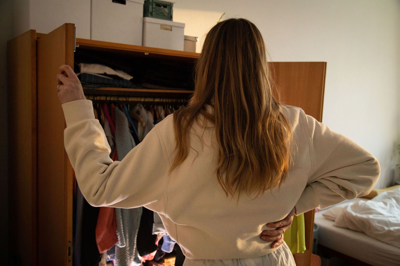 Eine Frau steht vor ihrem geöffneten Kleiderschrank