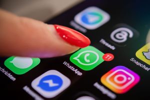 Eine Frau tippt auf einem Smartphone auf das WhatsApp-Symbol