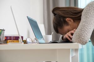 Eine junge Frau legt den Kopf auf den Tisch