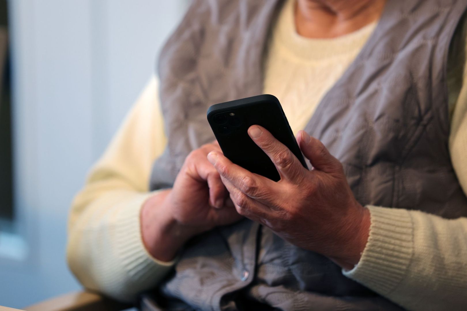 Eine Seniorin schreibt eine Nachricht in ihr Handy