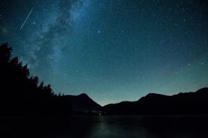 Eine Sternschnuppe leuchtet am Himmel über dem Walchense (Bayern)