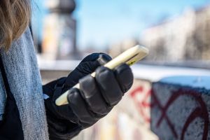 Eine warm angezogene Frau hält bei Kälte ein Handy