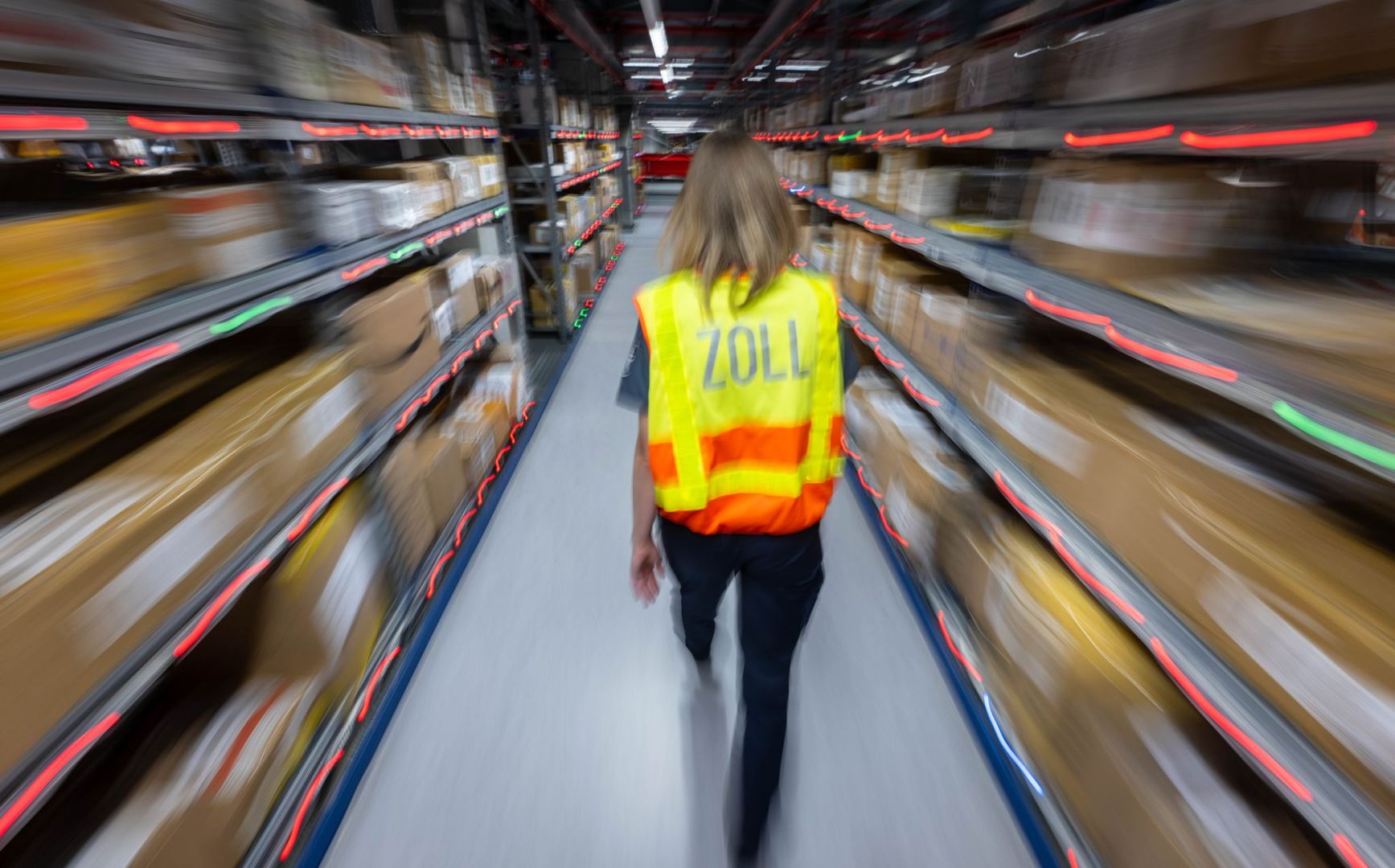 Eine Zollbeamtin läuft durch ein Paketlager