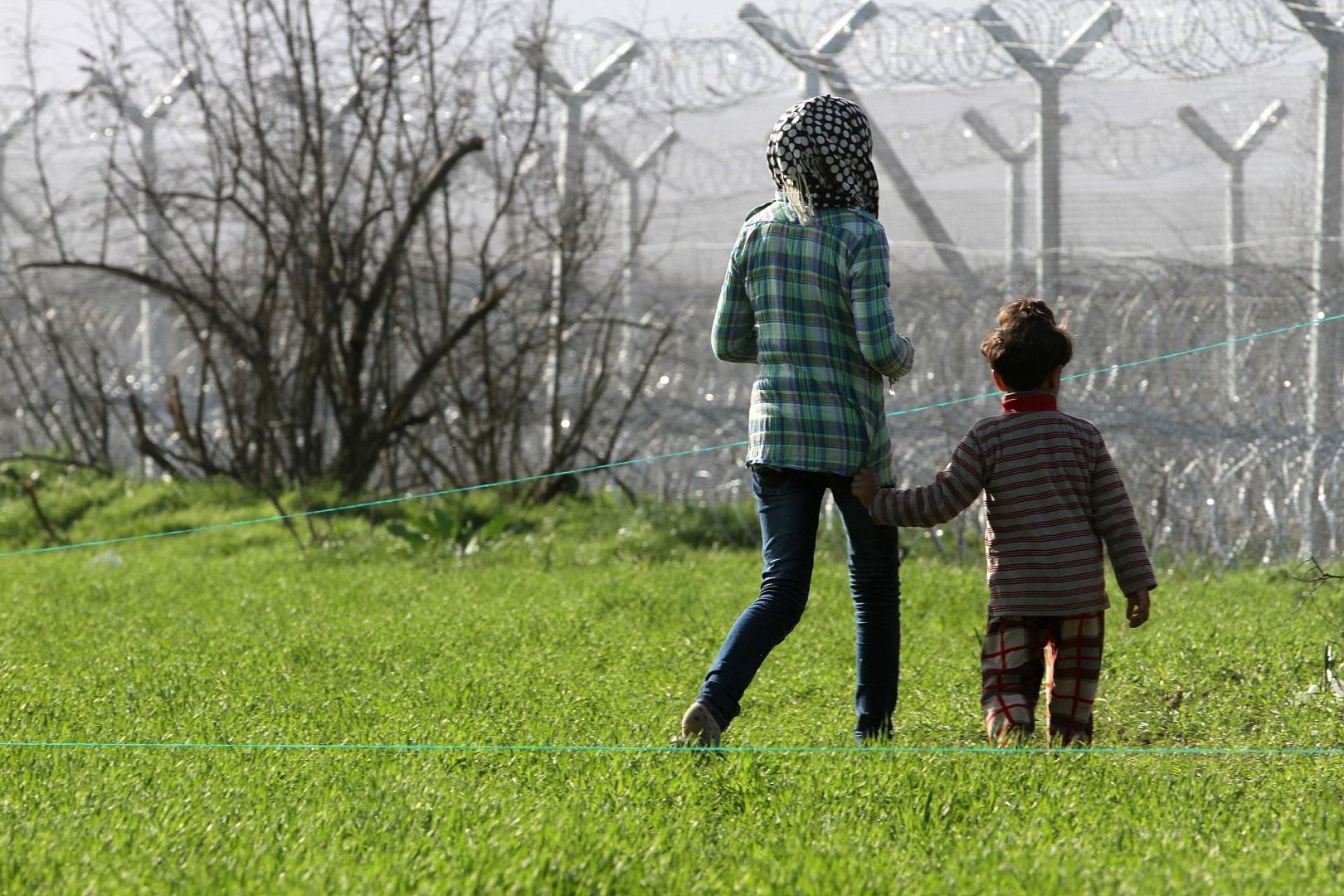 Flüchtlinge vor einem Grenzzaun (Archiv)