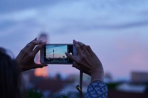 Frau fotografiert mit dem Smartphone den Abendhimmel über Berlin
