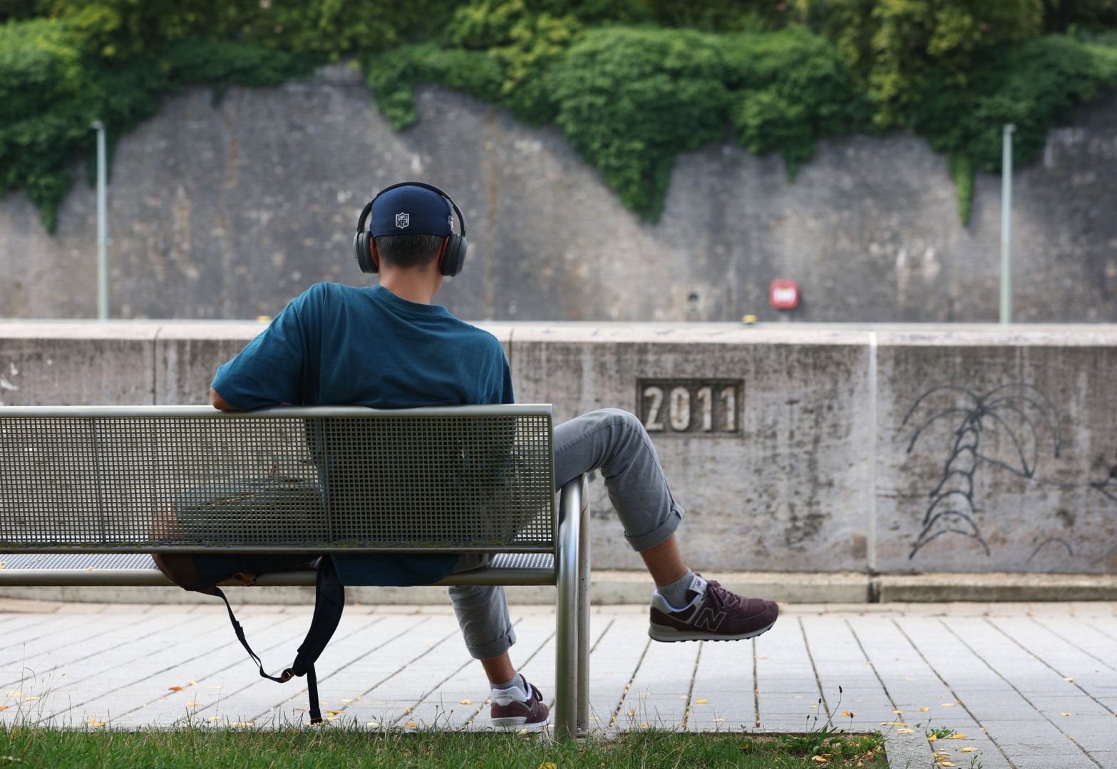 Junger Mann sitzt mit Kopfhörer auf einer Bank