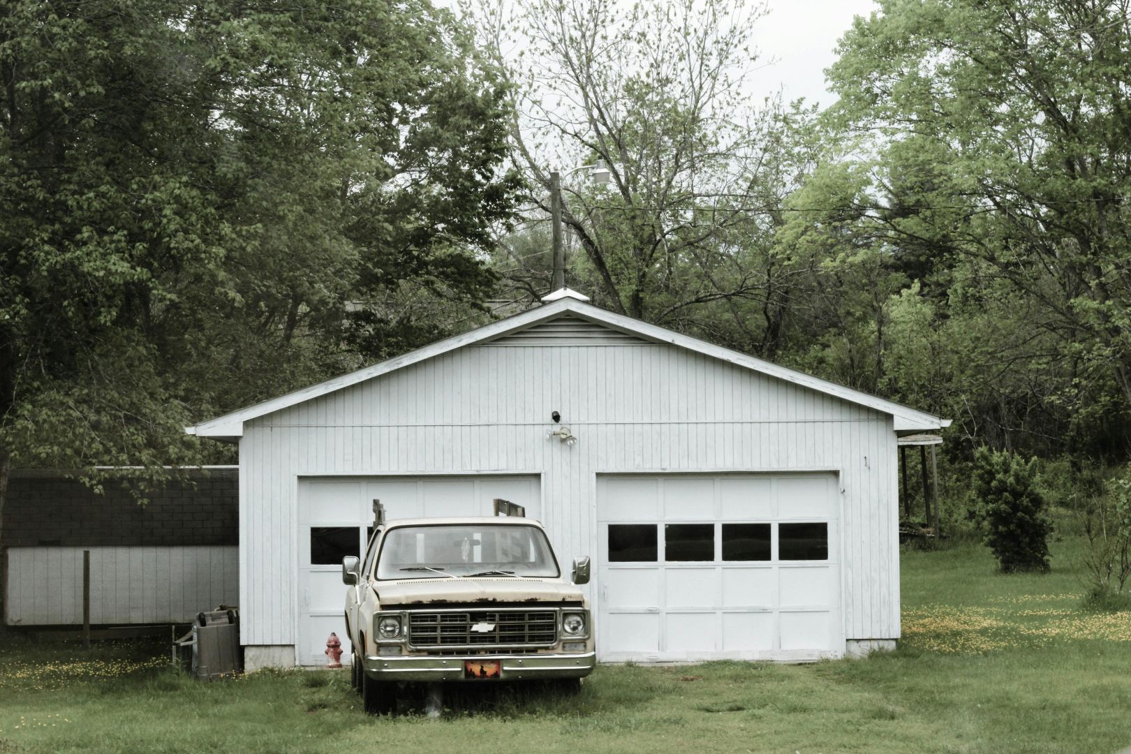 Klassischer Weißer Chevrolet Pickup In Der Nähe Der Weißen Zweitürigen Garage In Der Nähe Von Bäumen
