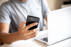 Mann mit Smartphone und Laptop