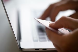 Mann sitzt mit Kreditkarte vor einem Laptop