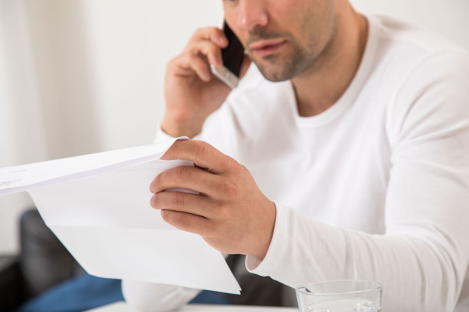 Mann telefoniert mit einem Brief in der Hand