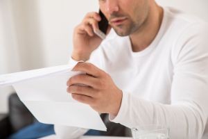 Mann telefoniert mit einem Brief in der Hand