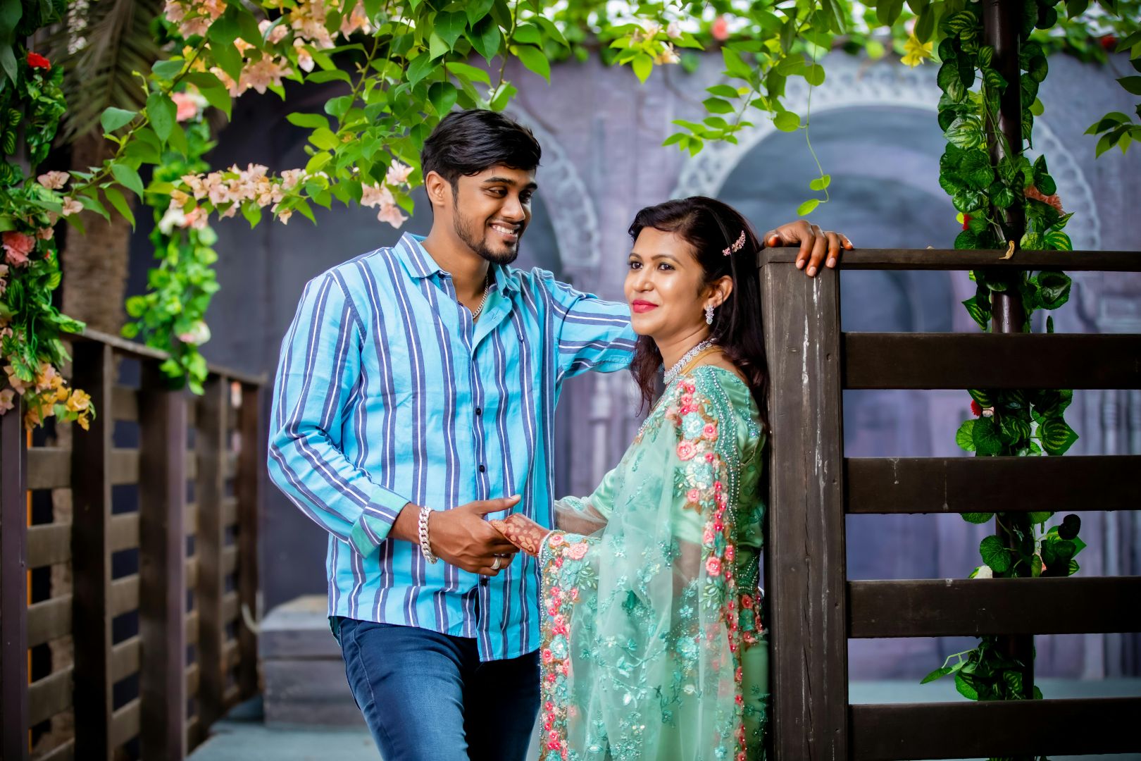 Paar posiert vor einer blumigen Kulisse im Freien, perfekt für ein Hochzeitsfoto.