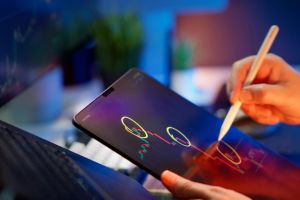 Person, die Kryptowährungstrends auf einem Tablet mit digitalem Stift analysiert.