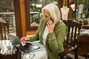 Seniorin mit Smartphone und Laptop