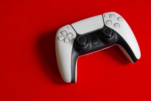 Weißer DualSense-Controller für PlayStation 5 auf auffälligem roten Hintergrund, der die moderne Gaming-Technologie betont.