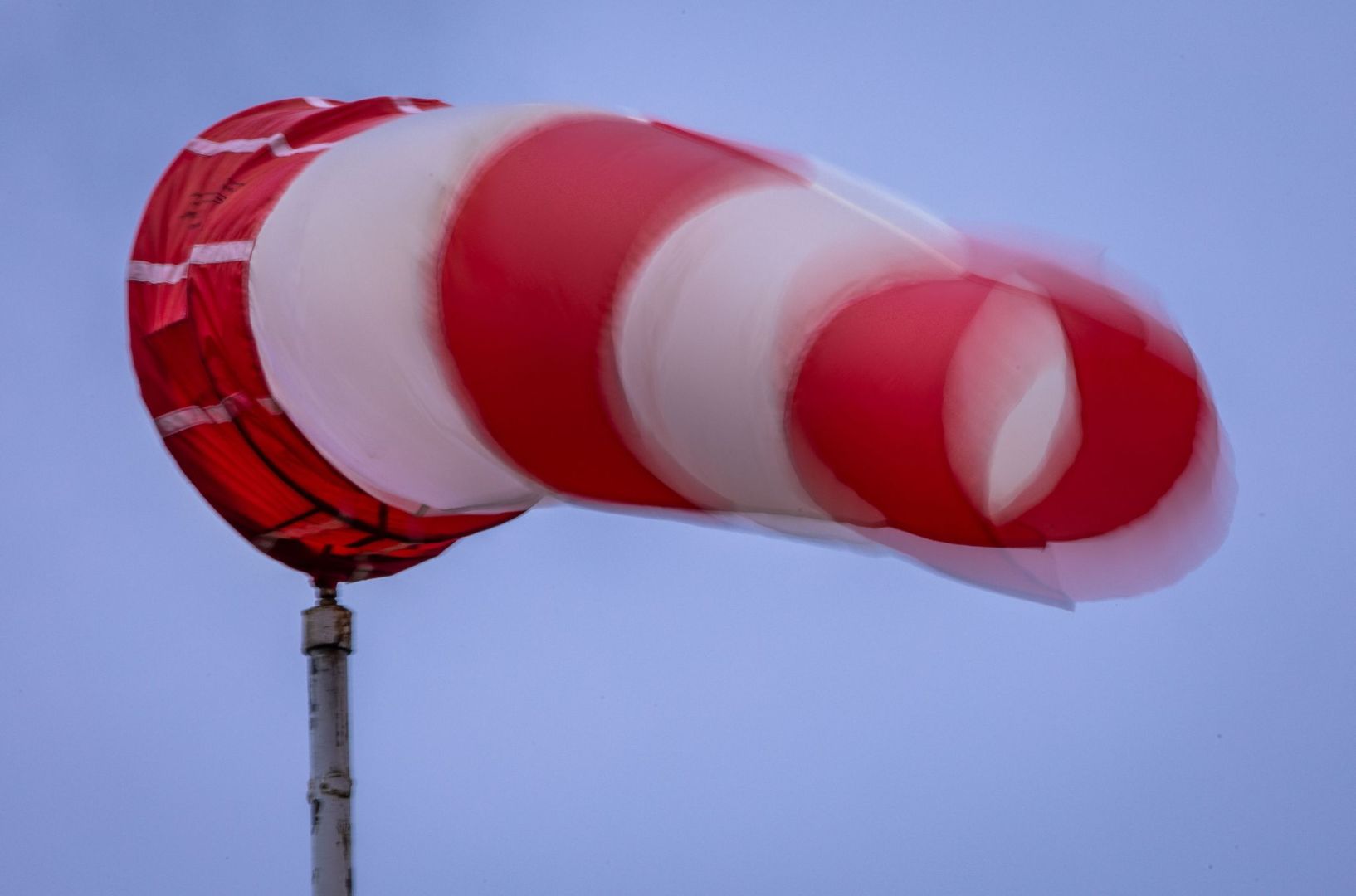 Windsack weht bei Regen und kräftigem Wind am Mast
